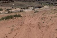 there is a motorcycle parked on the sand in the desert between two hills and large rock formations