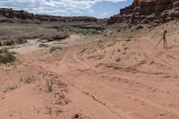 there is a motorcycle parked on the sand in the desert between two hills and large rock formations