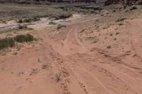 there is a motorcycle parked on the sand in the desert between two hills and large rock formations