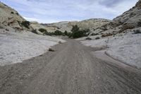 a mountain road is bordered by rocks and sand, which make a narrow curve down the trail