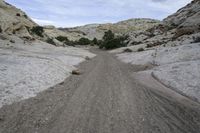 a mountain road is bordered by rocks and sand, which make a narrow curve down the trail