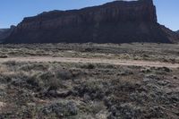 a view of a large mountain next to an empty area with plants and brush on it