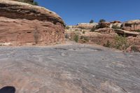 there is a man with a hat walking on a hill looking at the rock area