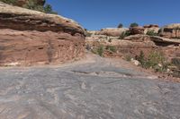 there is a man with a hat walking on a hill looking at the rock area