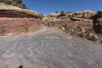 there is a man with a hat walking on a hill looking at the rock area