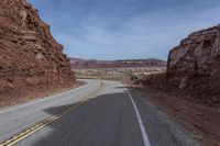 a motorcycle travels down the road between some rocks and the desert plain in arizona, usa