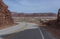 a motorcycle travels down the road between some rocks and the desert plain in arizona, usa