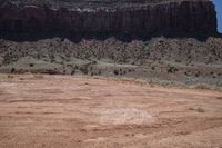 this is a horse standing on a dry, arid hill side that's surrounded by rocks