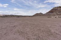 an empty desert area with rocks and rocks scattered about in it and blue sky with white clouds