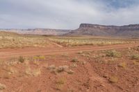 red dirt, and sparse grass, is in the background and is vast terrain and high cliff cliffs