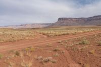 red dirt, and sparse grass, is in the background and is vast terrain and high cliff cliffs