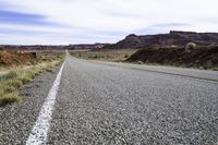 a large open road runs between two mountains near a canyon in the desert during winter