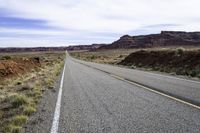 a large open road runs between two mountains near a canyon in the desert during winter