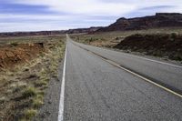 a large open road runs between two mountains near a canyon in the desert during winter