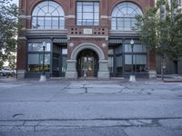 a large red brick building that has a clock on it's front entrance and doors