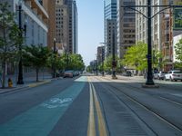 an empty street with buildings and parked cars on the sidewalks and green lanes on the sidewalk