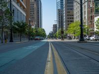 an empty street with buildings and parked cars on the sidewalks and green lanes on the sidewalk