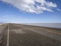 the road is empty with no people on it and is near the ocean in the background