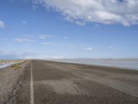 the road is empty with no people on it and is near the ocean in the background