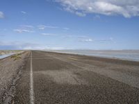 the road is empty with no people on it and is near the ocean in the background