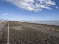 the road is empty with no people on it and is near the ocean in the background