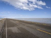 the road is empty with no people on it and is near the ocean in the background