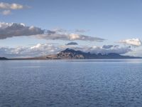 a large body of water with mountains on both sides of it and clouds in the sky