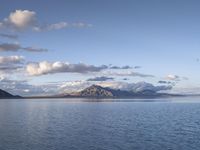 a large body of water with mountains on both sides of it and clouds in the sky