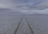 a road leads away from the ocean towards a vast expanse of snow - covered ground