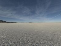 an empty desert is shown with blue skies and clouds above it in this image, there are two people and one is taking a picture