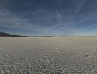 an empty desert is shown with blue skies and clouds above it in this image, there are two people and one is taking a picture