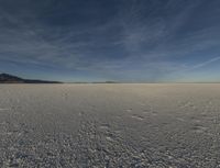 an empty desert is shown with blue skies and clouds above it in this image, there are two people and one is taking a picture