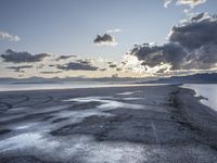 sunset behind storm clouds over an empty beach area with puddles of water and concrete