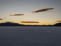 a lone bike is riding across the desert at sunset and snow is covering the landscape