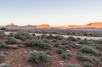 a wide shot of an island in the middle of the desert with mountains and a blue sky at dusk