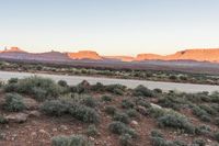 a wide shot of an island in the middle of the desert with mountains and a blue sky at dusk