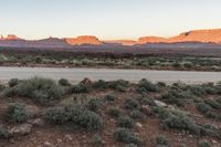 a wide shot of an island in the middle of the desert with mountains and a blue sky at dusk