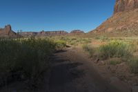 a man on his bike travels through a canyon area, looking forward while holding a saddle