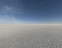 an empty desert with a clear sky and clouds in the background a few feet apart from a flying camera