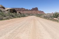 an empty dirt road in the middle of a desert mountain side area of rocks and scrubs with dirt