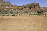 a person riding on top of an unpaved dirt field in front of tall red rocks