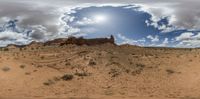 a person riding their bike through the desert on dirt and rock formations with a bright sun in the middle