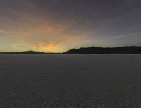 a sunset is seen over a vast desert plain with a person standing on one step