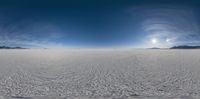 a 360 - view image of the desert and the sun behind them, with only one cloud