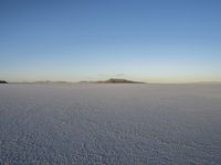 a person on the ground walking across the desert with their back to the camera while looking at an island