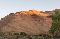 a person riding a bike down a dirt road with cliffs in the background at dusk