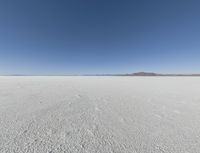 a wide shot of a barren plain in the distance with the sky and mountains in the background