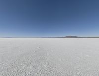 a wide shot of a barren plain in the distance with the sky and mountains in the background