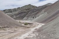 a dirt road going through a small rocky hill area of a desert with small vegetation in the middle