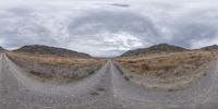 a panoramic picture of some desert dirt road with rocks and grass in the background